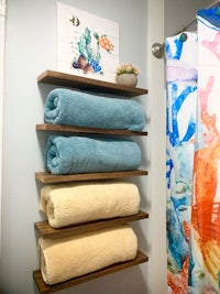 a bathroom with towels hanging on a wooden shelf